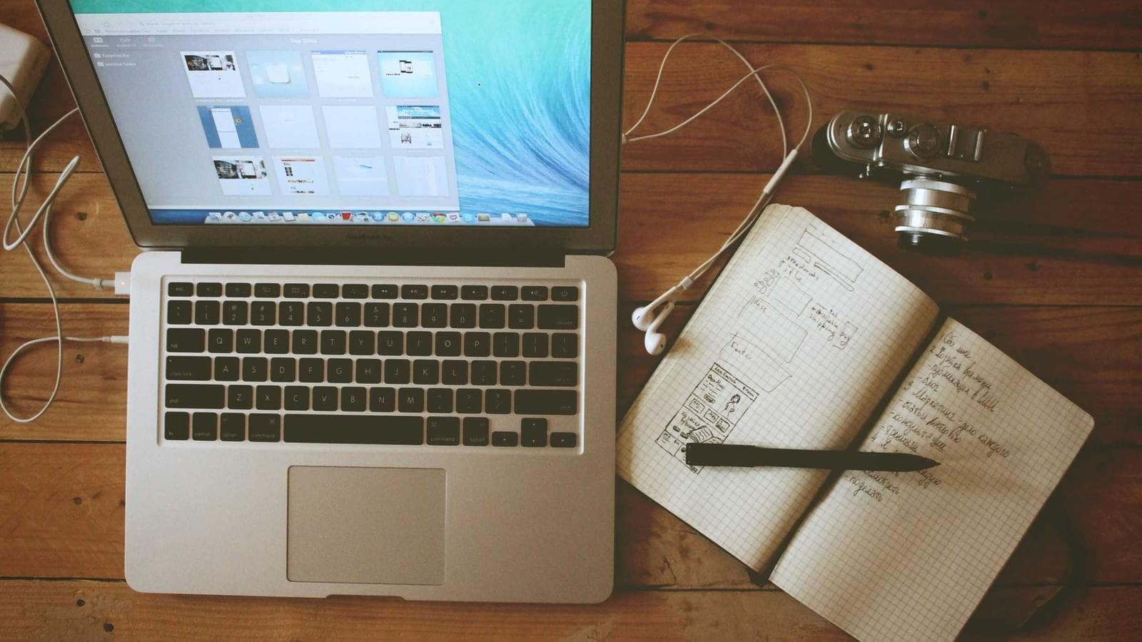 Laptop mit Website-Vorschauen neben einem Notizbuch mit Skizzen