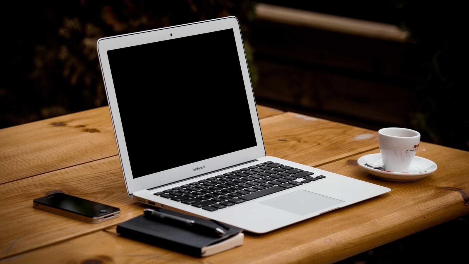 Aufgeräumter Schreibtisch mit Laptop, Notizbuch und Kaffeetasse