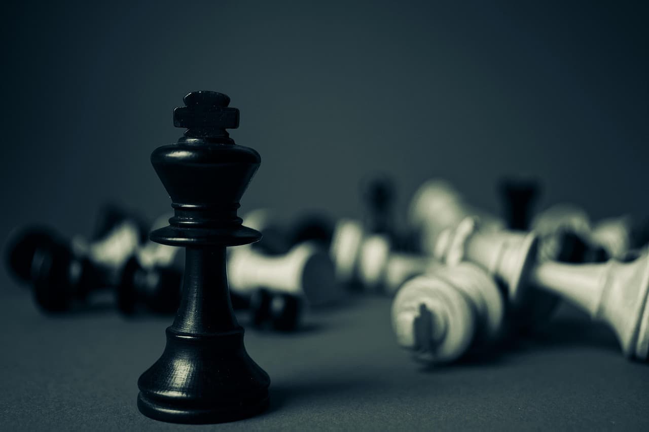 Schwarze Schachfigur König steht aufrecht, weiße Figuren liegen umgekippt — Sinnbild für strategische Entscheidungen